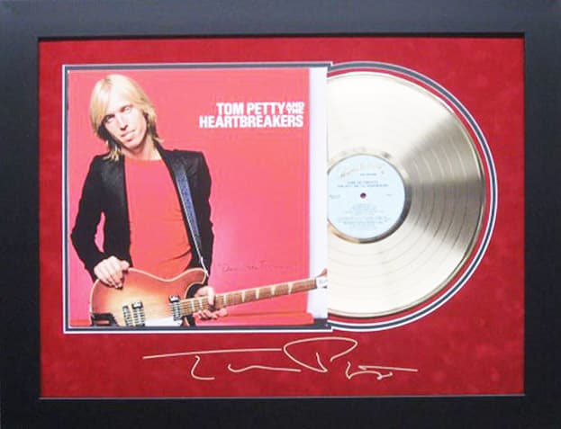 Framed gold record displayed beside the Tom Petty Damn the Torpedoes album cover with a laser-reproduced signature, offered as a charity auction lot